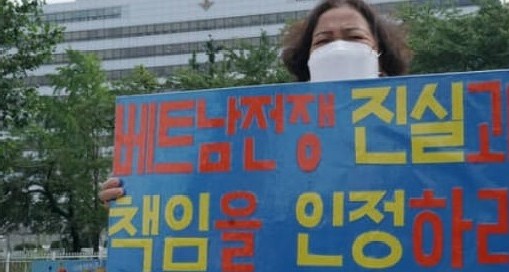 사진 설명 : 베트남 민간인 학살 생존자인 응우예티탄씨가 들고 서 있는 피켓에 “베트남전쟁 진실과 책임을 인정하라“라고 쓰여있다.