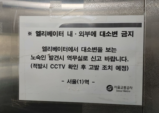 엘레베이터에 붙어있는 게시물. “엘레베이터에서 대소변을 보는 노숙인 발견시 역무실로 신고 바랍니다. 적발시 CCTV 확인 후 고발 조치 예정“ 이라고 적혀있다..